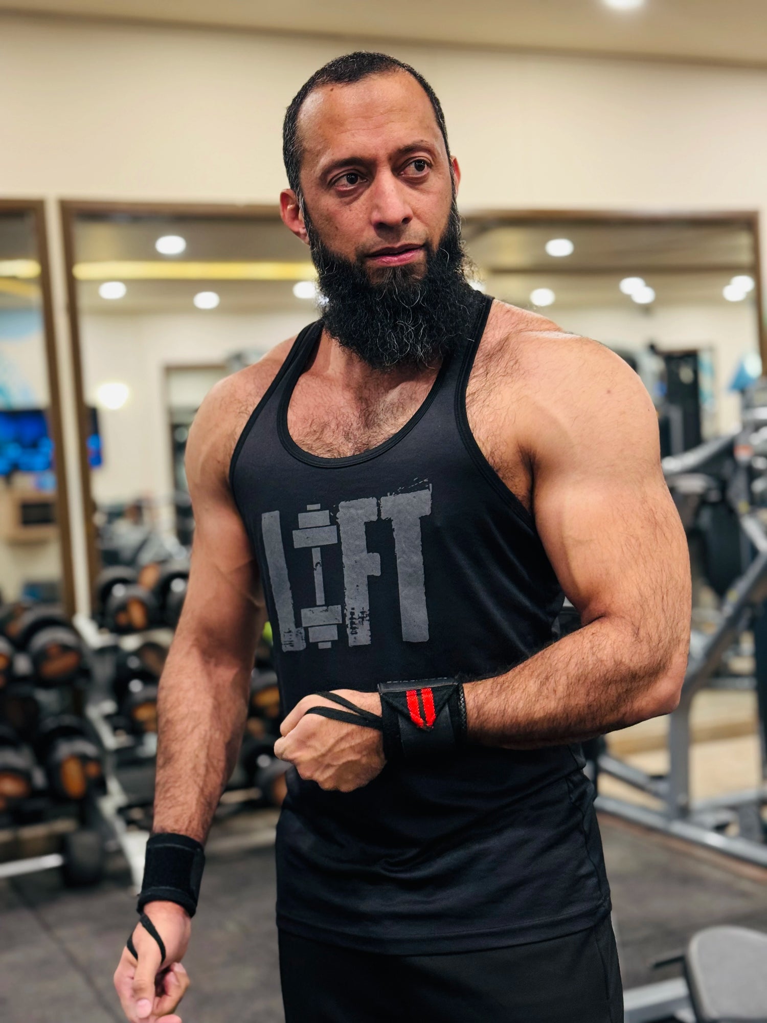 MetaMuscle Nutrition founder in a gym wearing a black tank top with "LIFT" printed on it.